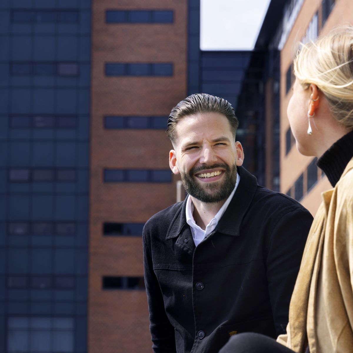 mørkhåret person smiler mod en lyshåret person i højre side