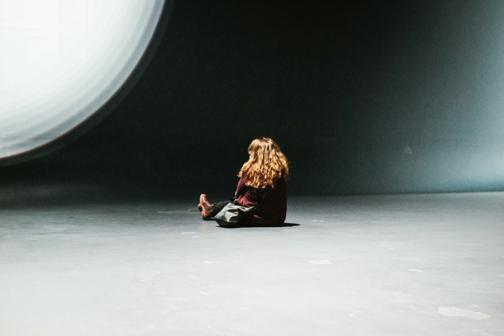 person sidder med ryggen vendt til på et gulv