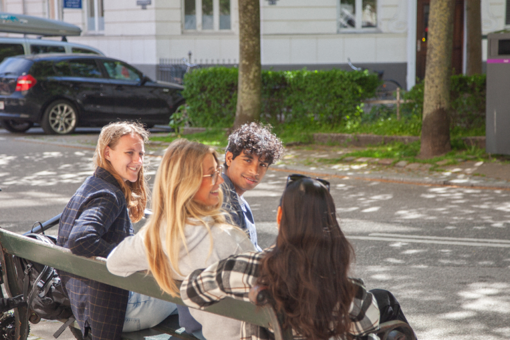 Studerende sidder på en bænk og konverserer