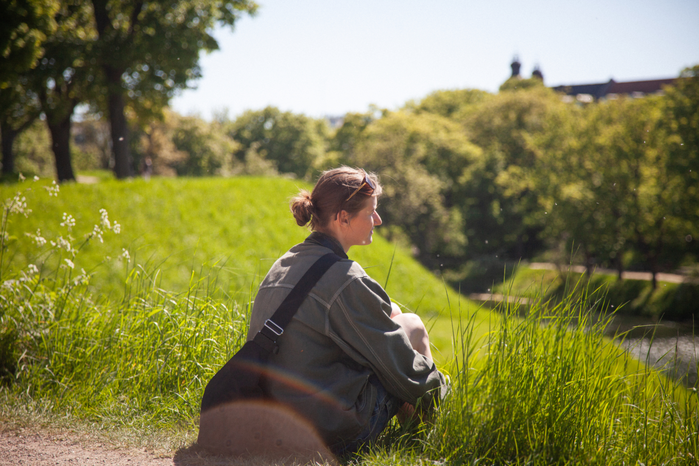 Pige i grå jakke sidder og kigger udover natur