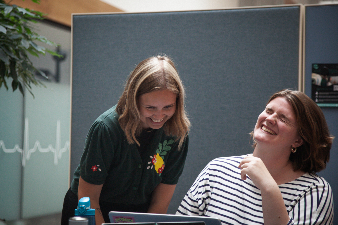 To kvinder griner imens de ser ind i en computerskærm